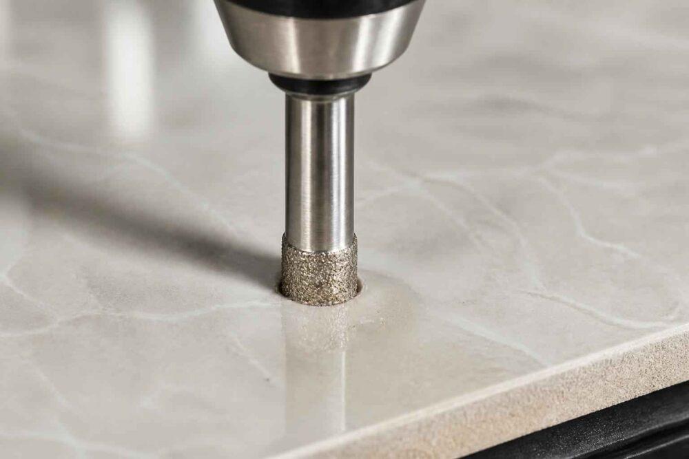 Wiertarka z diamentową otwornicą wiercąca otwór w jasnej płytce ceramicznej